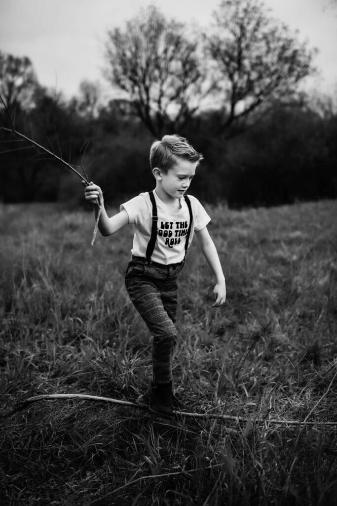 Family Photographer, a young boy flys a kite in a grassy field.